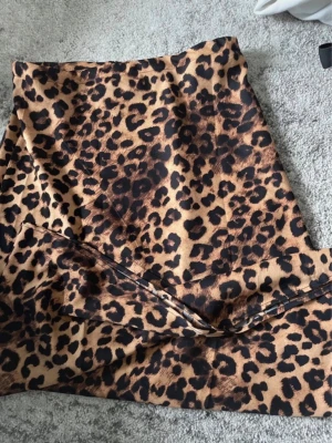 Leopardmönstrad långkjol - Säljer en snygg långkjol med leopardmönster i bruna och svarta toner. Kjolen har en rak passform och är tillverkad i ett mjukt, följsamt material. Använd endast en gång. För tajt för mig. 