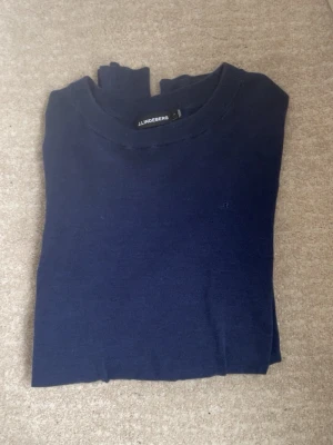 Blå långärmad tröja – J.Lindeberg - Stilren och tidlös långärmad tröja från J.Lindeberg i en snygg mörkblå nyans. Perfekt basplagg som funkar lika bra till vardag som till en mer uppklädd look. Mjuk och skön kvalitet med en minimalistisk design som aldrig går ur tiden. ✨ Passform: Klassisk/modern ✨ Skick: bra skick ✨ Ett måste i garderoben – lätt att matcha året runt!