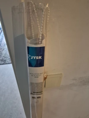 Rullgardin - Mörkläggande rullgardin från JYSK i vit färg. Kommer i originalförpackning med kedja för enkel upp- och nedrullning. Perfekt för att blockera ljus i sovrum eller vardagsrum. Enkel att montera och barnsäker. Har testat bara. Men passade inte till mitt fönster. Så den är annars i nyskick.