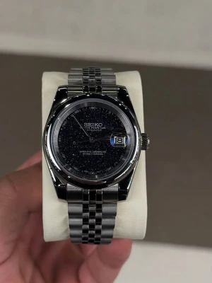 Seiko Galaxy Mod  -  Seiko Galaxy Mod  En väldigt unik seiko mod med Galaxy tavla, redo för att postas omgående, detaljerna i tavlan är glittrig och poppar verkligen under sol ljus. Bör ses I person.   - Urtavla och länk (rostfritt stål)  - Rörelse: Automatic NH35  - Box + resväska tillkommer vid köp  - Verktyg för att justera länk