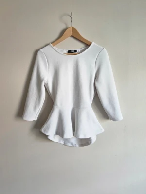 Vit topp med öppen rygg och volang  - Trendig och stilren ribbad peplumtopp med öppen rygg. Funkar lika bra till vardags som till fest - stylas enkelt med jeans, kjol eller kostymbyxor. ✨️  🤍Storlek: M men passar även S (säg till om mått önskas) 🤍Märke: Bikbok 🤍Färg: Vit  🤍Skick: Bra använt skick med mycket kvar att ge  ⚠️ Mindre skavanker  - 3 väldigt diskreta fläckar (se bilder) - lätt nopprighet på insidan  Inget som påverkar passform eller helhetsintryck
