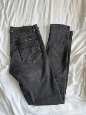 Tiger of sweden jeans - Säljer ett par svarta slim fit jeans med klassisk femficksdesign och dragkedjegylf. Jeansen har en snygg tvättad look och raka ben. Perfekta för dig som gillar en stilren och enkel stil.
