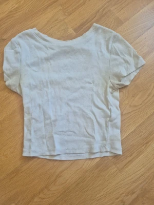 Ljusribbad kortärmad topp - En enkel och stilren ljus kortärmad topp med ribbad struktur. Lite deo fläckar vid armhålorna 