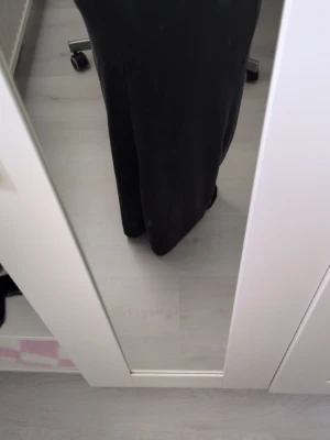 Svart långkjol i mjukt material - En enkel och stilren svart långkjol med rak passform. Kjolen är gjord i ett mjukt och följsamt material som ger en snygg siluett. Perfekt att matcha med en crop top eller stickad tröja för en trendig look.