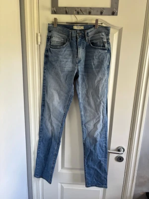 Blend Ljusblå raka jeans med hög midja - Snygga ljusblå jeans med raka ben och hög midja. Klassisk femficksmodell med diskreta slitningar och ljus tvätt. Jeansen har en enkel design och passar perfekt till en avslappnad stil. Materialet är denim i bomull.