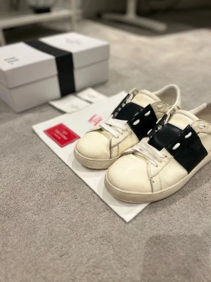 Valentino Garavani Open Sneakers – Strl 42 – Äkta – Fynd - Säljer ett par Valentino Garavani Open sneakers i storlek 42. Skorna är använda men i okej skick, perfekt för dig som vill ha ett par Valentino till ett riktigt bra pris.  ✔️ Nypris ca 4 000–6 000 kr ✔️ Original nya skosnören sitter på ✔️ Original box, dustbag och kort ingår (se bilder)  Skorna har normalt slitage (se bilder), men fortfarande mycket liv kvar och sitter snyggt på foten.  💰 Pris: 900 kr – fynd 