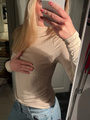 Beige polotopp med lång ärm - Snygg beige polotopp med lång ärm och tight passform. Perfekt att styla med jeans eller kjol för en clean och enkel look. Tunn och stretchig, passar bra till lager-på-lager outfits.