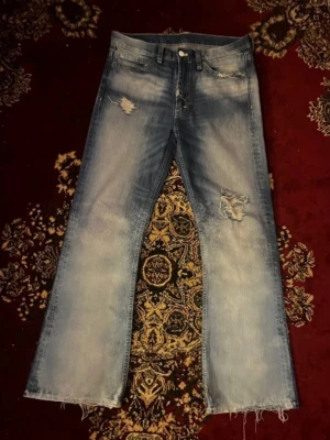 Vintage Bootcut Lightwash Jeans - Väldigt sällan använda eftersom de är lite för små för mig. Nästan helt nya, färgen och hålen är design :)      Längd: 113cm     Innebenslängd: 81cm         Benöppning: 27cm     Midja: 44cm