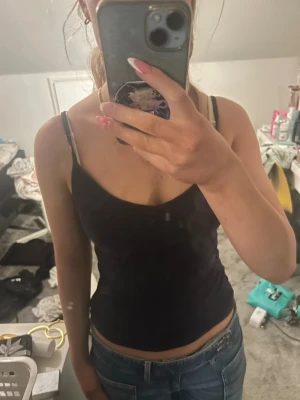 Mörk blå enkel linnetopp - Säljer en mörk blå, ärmlös linnetopp med smala axelband. Toppen har en enkel och stilren design som passar perfekt till jeans eller kjol. Materialet känns mjukt och stretchigt, vilket gör den bekväm att bära hela dagen.