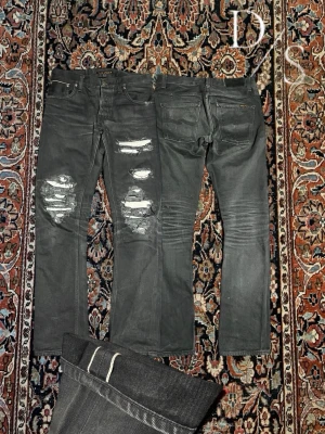 Nudie distressed Selvedge jeans - Riktigt snygga Svarta selvedge nudie jeans med coola slitningar. Slitningarna har tyg under och visar ingen hud. Modell: grim Tim Midja:40cm längd:100cm benöppning:17,5cm