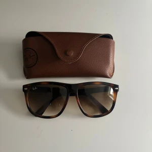 Ray-Ban Boyfriend solglasögon brun - Snygga Ray-Ban Boyfriend solglasögon med brunmelerad båge och mörka glas. Klassisk fyrkantig form och levereras med originalfodral i brunt konstläder. Perfekta för att lyfta din stil under soliga dagar. Nypris 1800 kr