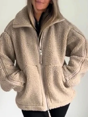 Beige oversized teddyjacka - Mysig beige teddyjacka med dragkedja framtill och hög krage. Jackan har en oversized passform och stora fickor på sidorna. Perfekt för att hålla sig varm och se trendig ut under kyliga dagar.