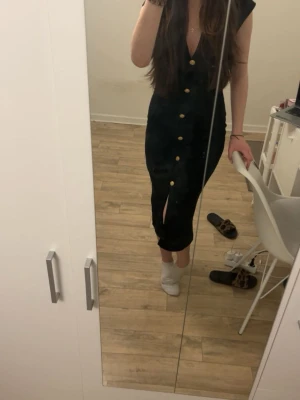 Svart klänning med knappar från Zara - Svart klänning med v-ringning, guldiga knappar framtill och en slits nedtill, Aldrig använd! 