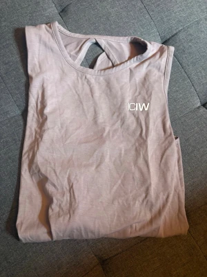 Ljuslila ärmlös topp från ICANIWILL - Snygg ljuslila ärmlös topp från ICANIWILL med diskret logga på bröstet. Toppen har en rund halsringning och ett sportigt snitt med öppen ryggdetalj. Perfekt för dig som gillar en stilren och bekväm look.