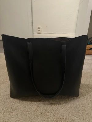 Svart handväska  - Svart stor rymlig handväska. Köpt på Zalando. Något sliten i kanterna upptill. 