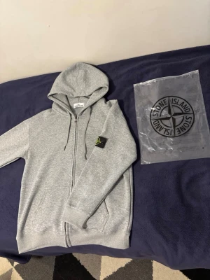 Stone island grå hoodie  - En skön och fin stone island kofta hoodie. Den är bekväm och har ett skönt material i insidan. Den är ny utan prislapp. Den kommer med original förpackning. Kontakta för fler bilder.