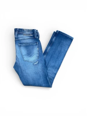 Blå slitna jeans från Broken Edge - Snygga blå jeans från Broken Edge med slitningar och trasiga detaljer framtill. Klassisk femficksmodell med raka ben och normal midja. Perfekta för en avslappnad och trendig look. Materialet är bomull med stretch för extra komfort.