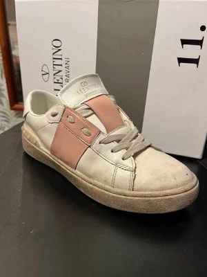 Valentino Garavani vita sneakers - Snygga vita sneakers från Valentino Garavani med bred rosa detalj, sänker pris vid snappat köp, tvättar innan jag skickar!