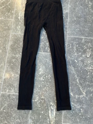Svarta ribbade leggings från Zara - Säljer ett par svarta leggings från Zara i storlek 152 (11-12 år). De är ribbade och har en hög midja som sitter skönt. Perfekta för träning. Materialet är mjukt och stretchigt för extra komfort.