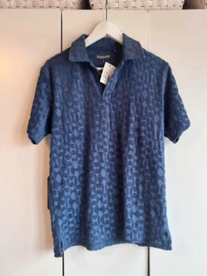 Blå mönstrad piké. Frotté. S.  - Blå med mönster i frottén. Mjuk, sval o skön. Perfekt timl sommaren. Storlek S. Från Kappahl. Ny. Finns inget att anmärka på. Lapparna kvar. NWT. 