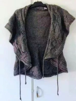 Snygg Stickad Väst I Ullblandning - Made In Italy - Jättefin kabelstickad väst/tröja i en mörkgrå färg. Den är tillverkad i Italien och håller hög kvalitet. Perfekt att bära över en skjorta eller klänning för en snygg lager-på-lager-look! Passar perfekt nu till våren eller svala sommarkvällar! Material: 50% ull, 50% akryl Skick: Mycket fint skick, sparsamt använd.