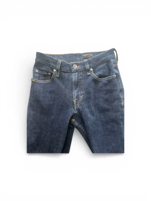 Tiger of sweden jeans - **Tiger of Sweden Jeans | Mörkblå | W27/L30**  Snygga Tiger of Sweden-jeans i en djup, mörkblå denim med den där lite lyxigare känslan som ToS är kända för. Ren skandinavisk design med läderdetalj bak och guldsömmar som lyfter helheten.  Slim fit som sitter riktigt bra – elegant nog för kontoret, casual nog för helgen.  **Tiger of Sweden-kvalitet till ett bråkdel av butikspriset. Passa på! 🐯**