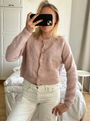 Ljusrosa stickad kofta med knappar💖💖 - Mysig ljusrosa stickad kofta med stora matchande knappar framtill. Koftan har rund halsringning, långärmad design och är tillverkad i ett mjukt material som ger en skön känsla. Perfekt att slänga på sig när det är lite kyligare.