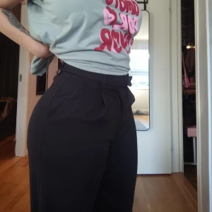 Svarta kostymbyxor från Gina Tricot  - Klassiska svarta kostymbyxor från Gina Tricot med raka ben och pressveck. Byxorna har hällor för skärp, två bakfickor med passpoal och stängs med hake och dragkedja. Materialet är slätt och ger en stilren look. Aldrig använda!