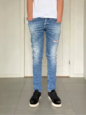 Ljusblå slitna slim jeans - Säljer ett par ljusblå skinny jeans med slitningar och hål på knäna. Jeansen har en klassisk femficksmodell och är tillverkade i denim med stretch för skön passform. Perfekta för en avslappnad och trendig look.