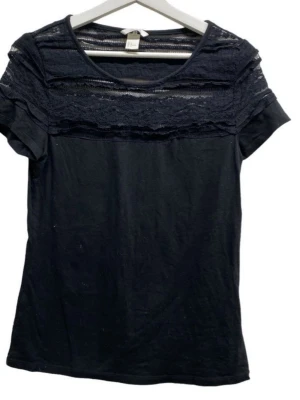 Svart topp med spets från H&M - Snygg svart topp från H&M med korta ärmar och rund halsringning. Överdelen har detaljer i spets och transparenta partier som ger en cool look. Tillverkad i mjukt tyg med spetsinslag upptill. Perfekt för dig som gillar stilrena men ändå unika plagg. Perfekt för sommar men också vinter