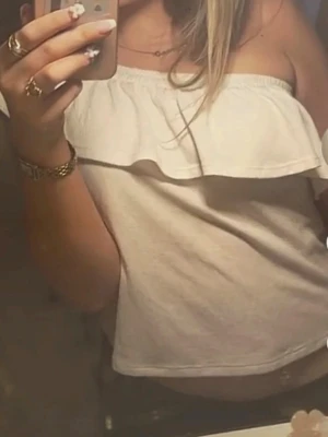 Vit oneshoulder topp med volang - Säljer en vit oneshoulder topp med bred volangdetalj längs halsringningen. Toppen är croppad och har en tight passform, perfekt för dig som gillar trendiga och feminina plagg. Materialet känns mjukt och stretchigt, troligen bomull eller polyester.