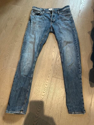 Blå jeans från Jack and jones - Säljer ett par blå slim fit jeans med lätt slitna detaljer och klassisk femficksdesign. Jeansen har normal midja och raka ben. Modellen är tapered Mike och storleken är 30/34. Säljer då de ej kommer till användning längre, hör av er för fler frågor😊