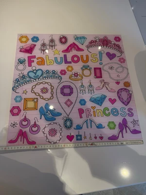 Färgglad prinsessposter med smycken - Stor poster med prinsesstema i rosa, lila, blått och gult. Motivet visar tiaror, smycken, klackskor, diamanter och texten 'Fabulous Princess' i färgglada bokstäver. Perfekt som dekoration till barnrum eller pysselhörna.