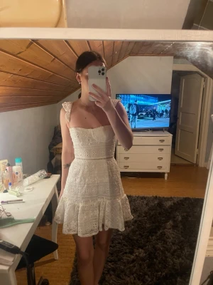 Vit spetsklänning med volang - Supersöt vit kortklänning med spetsdetaljer och volangkant. Klänningen har breda axelband med volanger, snörning i ryggen och en figurnära passform upptill. Perfekt för sommarens alla tillfällen! Köpt på shien för cirka 200kr. Använde denna på min student, men den är helt fläckfri och fortfarande mycket bra skick!