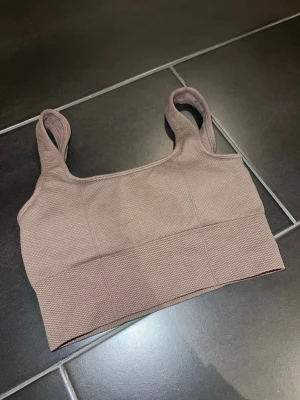 aimn brun topp - Brun topp med fyrkantig halsringning och breda axelband. Toppen är ribbad