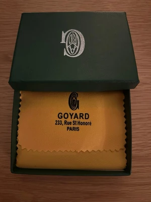 G svart korthållare i läder - Snygg svart korthållare från G med det klassiska vita och gråa mönstret. Tillverkad i exklusivt läder och levereras i original grön ask och gul tygpåse med logga. Perfekt för kort och ID, smidig att ha i fickan.