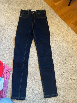 Mörkblå Molly jeans från Gina Tricot - Säljer ett par mörkblå Molly jeans från Gina Tricot. De har hög midja, smal passform och klassiska kontrastsömmar. Perfekta för dig som gillar en tight och bekväm stil. Jeans i stretchigt bomullsmaterial.