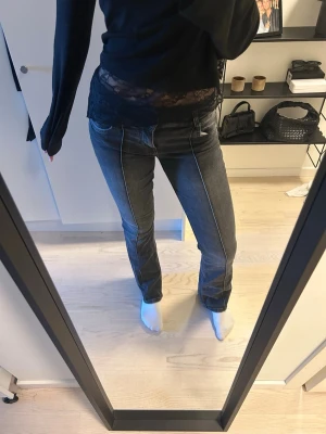 Grå jeans med kontrastsömmar - Säljer ett par grå jeans med raka ben och tydliga vita kontrastsömmar längs framsidan. Jeansen har low/mid waist, dubbla knappar och klassiska fickor fram och bak. Materialet är stretchigt denim som sitter snyggt och bekvämt💕