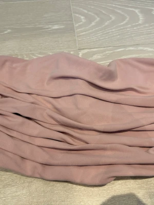 Rosa bandeau tubtopp  - Säljer en ljusrosa bandeau tubtopp med draperad effekt. Toppen är axelbandslös och har en tight passform som sitter snyggt på kroppen. Perfekt att matcha med höga jeans eller kjol för en trendig look.