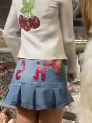 Harry Styles kjol med glitter och volang - Säljer en kort blå Harry Styleskjol med glittriga detaljer och stora rosa H S bak. Kjolen har volangkant och små vita pärlor framtill för extra bling. Storlek 34 och har en liten fläk - se bild 