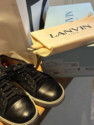 Svarta Lanvin DBB1 - Snygga svarta sneakers från Lanvin i äkta läder med vita sulor och svarta skosnören. Skorna är äkta och kommer med allt og😊