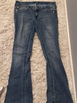 Blå bootcut jeans från True Religion - Säljer ett par blå Lågmidjade bootcut jeans från True Religion med Rosa sömmar i Modell joey. Storlek W28💞 pris kan diskuteras