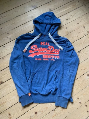 Superdry Hoodie  - Säljer denna Superdry hoodie. Skick 8/10. Storlek L men passar även M. Priset in diskuteras vid snabb affär.