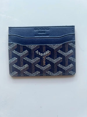 Mörkblå G*yard korthållare - Snygg mörkblå korthållare från G*yard med det klassiska mönstret i vitt och brunt. Tillverkad i läder och canvas med flera fack för kort. Perfekt accessoar för dig som vill ha något stilrent och exklusivt i fickan.