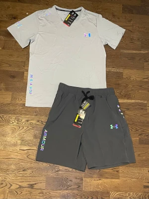 Under Armour Set - Snyggt träningsset från Under Armour med ljusgrå t-shirt och mörkgrå shorts.
