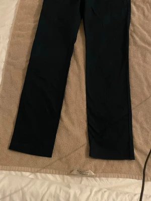 Mörkblå raka chinos från NNO7.  - Snygga mörkblå chinos med rak passform och klassisk design. Byxorna har diskreta sömmar och är tillverkade i ett mjukt, vävt material som ger en clean look. Perfekta för dig som gillar stilrena och enkla byxor.