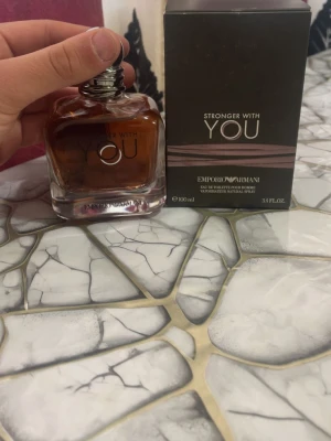 Emporio Armani Stronger With You EdT - Emporio Armani Stronger With You är en eau de toilette i en stilren glasflaska med rundade former och mörk bärnstensfärgad vätska. Flaskan har en silverfärgad kork och kommer i en elegant svart kartong med bronsdetaljer. Volymen är 100 ml.
