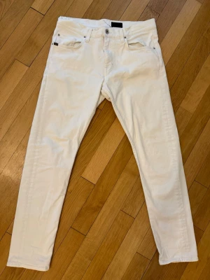Vita  jeans från Tiger of Sweden - Snygga vita slim fit jeans från Tiger of Sweden med klassisk femficksmodell och smal passform. Jeansen har normal midja, bälteshällor och är tillverkade i ett stretchigt bomullsmaterial för extra komfort. Perfekta för en clean och stilren look.