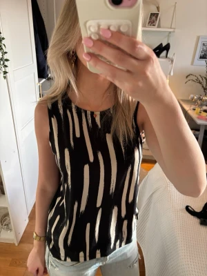 Svart och vit mönstrad topp  - Säljer denna snygga  ärmlösa linnetopp i svart och vitt mönster, perfekt till sommaren. Den är använd en gång men annars i helt nytt skick och har inga defekter ☺️☺️