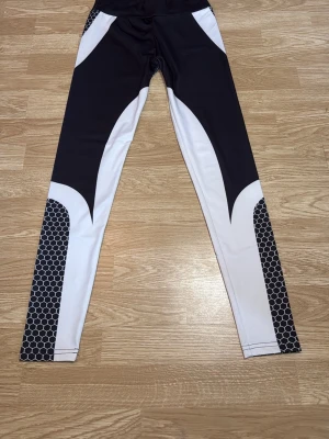 Svarta och vita leggings med mönster - Ett par träningsbyxor i svart och vitt med  bikakemönster på benen och bakdelen. I storlek S